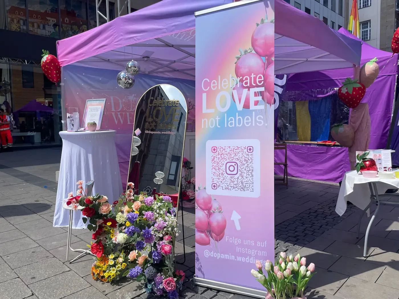 Infostand von Dopamin Weddings auf dem CSD München mit Regenbogenfahnen